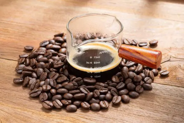 Espresso coffee in measuring cup the scale shows 30 millilitres or 1 ounce