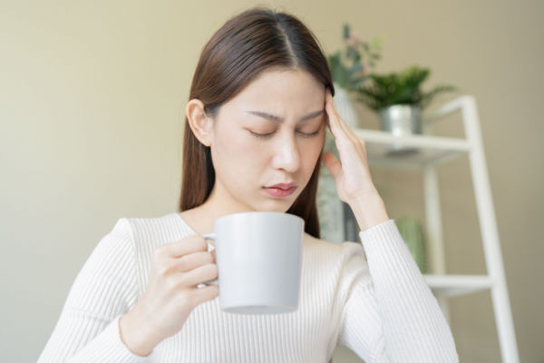 A woman feeling dizzy while drinking coffee